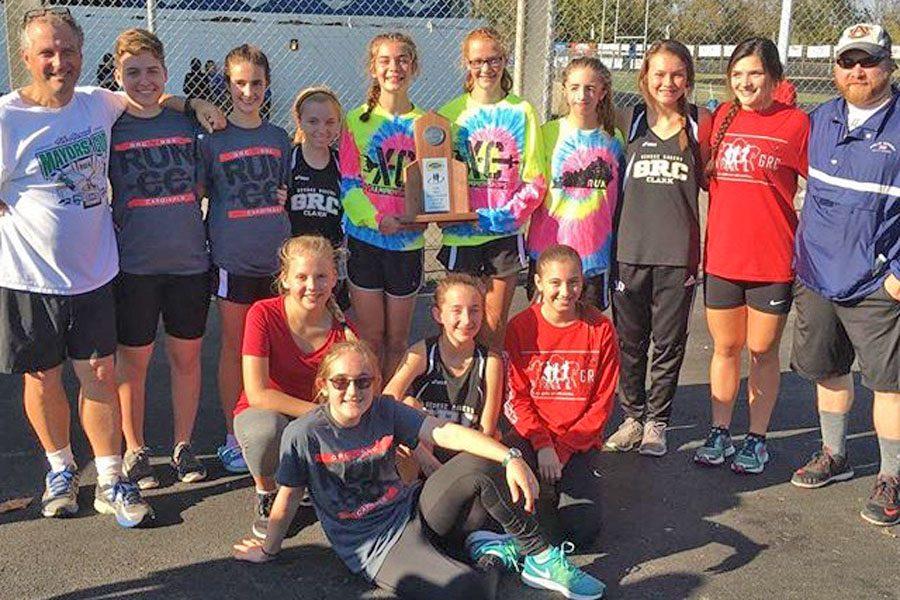 The girls cross country team poses with coaches and the regional runner-up trophy.